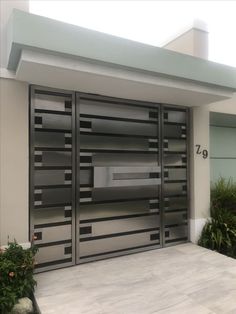 an image of a modern garage door with flowers in the foreground and plants on either side