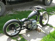 a motorcycle parked on the side of a road next to a green truck and grass