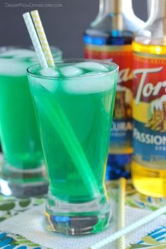 two glasses filled with green liquid and drinking straws