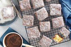 several pieces of cake on a cooling rack next to a cup of coffee