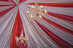 a chandelier hanging from the ceiling in front of red and white drapes