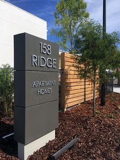 the sign for 156 ridge apartment homes in front of a fenced area with trees