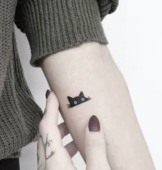 two people with matching tattoos on their arms holding each other's hands and one has a cat tattoo on it