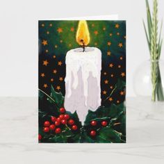 a lit candle with holly and red berries