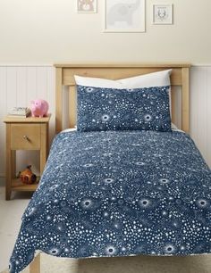 a bed with blue and white bedspread on top of it in a bedroom