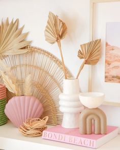 a white shelf topped with vases filled with flowers and seashells on top of it