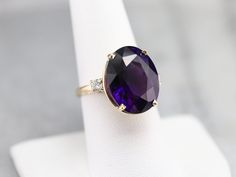 The focal point of this ring is absolutely the outstanding oval cut amethyst that we've set at the center. Bright sound cut diamonds light up the shoulders, bringing even more sparkle to this beautiful gem! Metal: 14K Yellow Gold Gem: Amethyst 13.59 Carats Gem Measurements: 17.3 x 13.2 mm, Oval Accents: 2 Diamonds totaling .26 Carats, I in Color, SI1 in Clarity Ring Size: 8 Oval Amethyst Ring With Gemstone Accents For Formal Occasions, Oval Amethyst Ring With Diamond Accents, Oval Brilliant Cut Amethyst Ring In Fine Jewelry Style, Oval Brilliant Cut Amethyst Ring Fine Jewelry, Oval Brilliant Cut Amethyst Ring, Oval Amethyst Ring With Diamond Accents For Anniversary, Elegant Oval Amethyst Ring With Diamond Accents, Anniversary Oval Amethyst Ring With Diamond Accents, Fine Jewelry Diamond Cut Oval Amethyst Ring