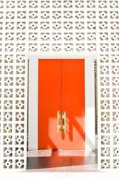 an orange and white door is in front of a wall with lattices on it