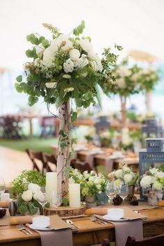 the table is set with candles, flowers and greenery for an outdoor wedding reception