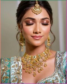 a woman in a blue and gold outfit with jewelry on her head, looking at the camera