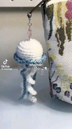 a small crochet doll is hanging from a zippered pouch on a hook