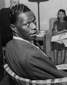 a black and white photo of a man sitting in a chair next to two women