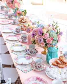 a long table with plates, cups and saucers filled with flowers on top of it