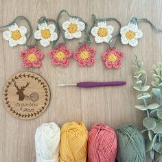 crochet flowers and yarn are arranged on a table next to a ball of yarn