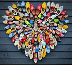 there are many pairs of colorful shoes arranged in the shape of a flower on this wall