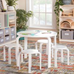 three white children's tables and chairs in a playroom with bookshelves