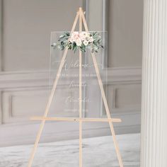 a wooden easel with a sign and flowers on it