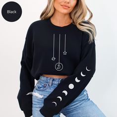 Embrace the enchanting allure of the night sky with our Mystic Moon Phases Sweatshirt (print sleeve). Adorned with intricate sleeve designs depicting the lunar cycle in shimmering gold, this cozy sweater is more than just apparel--it's a celestial masterpiece. Perfect for the dreamers and stargazers in your life, this mystical sweatshirt is a thoughtful gift that captures the magic of the moonlit sky. 👉 Unisex Sweatshirt Gildan 18000 - Unisex heavy blend crewneck sweatshirt is pure comfort. - Made with a medium-heavy fabric blend of 50% cotton and 50% polyester (100% ethically grown US cotton). - The blank tee's dyes are OEKO-TEX-certified dyes with low environmental impact. - Soft cotton and quality print (Direct-to-garment printing) make users fall in love with it over and over again. Moon Outfit Ideas, Moon Outfit, Moon Sweater, Sarcastic Clothing, Sweatshirt Print, Golden Moon, Mystic Moon, Moonlit Sky, Lunar Cycle