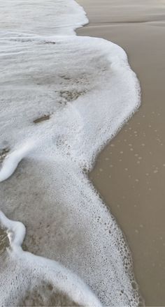 an ocean beach with waves coming in from the water and sand on the shore line