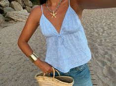 a woman on the beach taking a selfie with her cell phone and straw bag