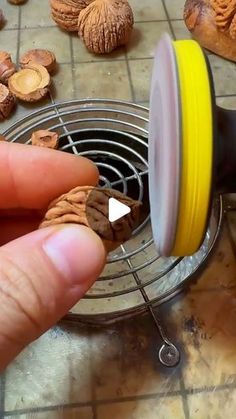 a hand holding a piece of food over a metal grate on top of a tile floor