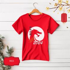 Chinese New Year Shirt, ideal to celebrate the year of the dragon. ~ About this T-shirt: Adult Unisex T-shirts: Soft cotton, great quality, light fabric with 100% Airlume combed and ringspun cotton, fiber content may vary for different colors. Ribbed knit collars to bolster shaping. Runs true to size. ~ Returns, Exchanges & Cancellations When you place an order, we customize the item and send it to production. Therefore, we cannot accept returns, exchanges or cancellations at this point. If you made a mistake on your personalization text or need to change the text, please contact us within 2 hours of placing your order. ~ Care Instructions Machine wash cold (max 30C or 90F), do not bleach, do not tumble dry, do not iron, do not dry clean.  ~ Notes The position of the design, as well as the Red Short Sleeve T-shirt For Gift, Red Short Sleeve T-shirt For Gifting, New Year Red T-shirt With Graphic Print, Red Graphic Print T-shirt For New Year, Red Short Sleeve T-shirt For New Year, Red Short Sleeve Shirt For Gift, Red Short Sleeve Shirt As Gift, New Year Graphic Print Short Sleeve T-shirt, Chines New Year