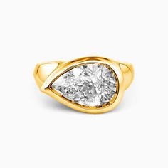 a yellow gold ring with a pear shaped diamond in the center, on a white background