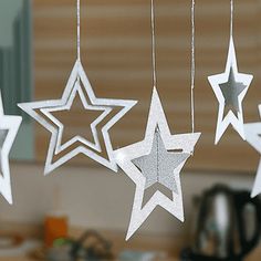 five white stars hanging from strings in a kitchen