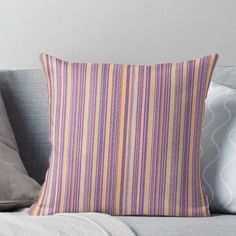 a striped pillow sitting on top of a couch next to a gray pillow case and two pillows