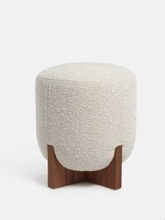 a white stool with wooden legs and a round foot rest on the top of it