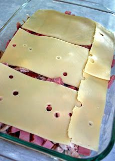 a glass baking dish filled with ham and cheese slices, cut into four equal squares