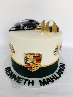 a white cake with black and gold frosting on the top has a porsche logo