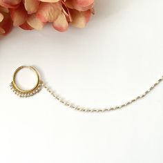 a close up of a necklace with a flower in the background