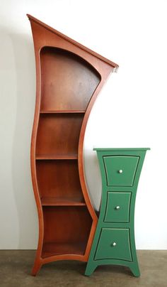 a green cabinet next to a tall wooden bookcase with drawers on each side and an open shelf in the middle