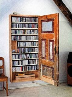 an open bookcase with many books on it in a room next to a chair