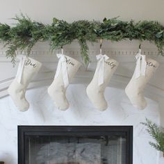 stockings hanging from the mantle with greenery on them, and personalized stocking