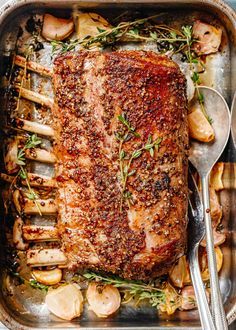 a roasting pan with meat, potatoes and herbs on it is ready to be cooked