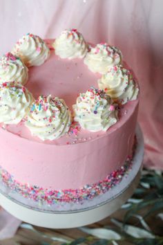 a pink cake with white frosting and sprinkles