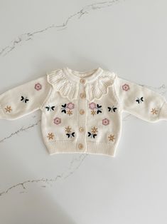 This Knit Floral Cardigan is perfect for your little one! With its intricate floral embroidery and dainty little buttons, your baby will be lookin' cute as a button. And the ruffled hollow collar? Beyond adorable! Keep your little bloom at the height of fashion with this cozy knit cardigan. Cute Cream Cotton Cardigan, Spring Cotton Cardigan For Playtime, Cute Spring Sweater For Playtime, Cute Spring Cardigan For Playtime, Cute Cotton Cardigan With Button Closure, Spring Long Sleeve Cardigan For Playtime, Spring Playtime Long Sleeve Cardigan, Cotton Cardigan With Button Closure, Cute Style, Cute Long Sleeve Embroidered Cardigan