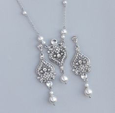 two necklaces with pearls and diamonds on a gray background, one is wearing a tiara