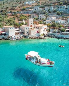 an aerial view of a small boat in the water near a village and beach area