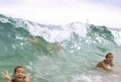 two people in the water with their arms out and one person on a surfboard