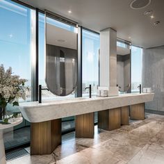 a bathroom with two sinks and mirrors in front of large windows that look out onto the ocean