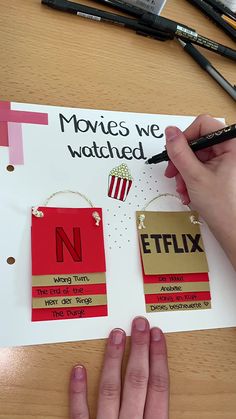 a person is holding a pen and drawing on some movie themed magnets that are attached to a piece of paper