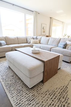 a living room with a large sectional couch and coffee table in front of the window