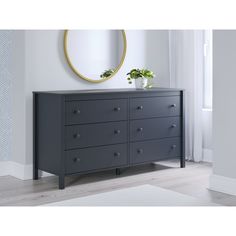 a black dresser with two potted plants on top and a round mirror above it