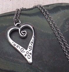 This is such a unique and whimsical heart pendant necklace.  It has incredible detail and another little heart showcased inside the main heart.  This would make a very sweet and meaningful gifts for a loved one on any occasion.  The heart measures 1” long by 5/8” wide and is made from allergy free plated silver.  It hangs from a simple 18” stainless steel necklace chain.I have matching earrings in my shop, if you would like the whole set.  Here is the link........... https://etsy.me/30EwF2x Than Silver Spiritual Heart Charm Necklace, Metal Heart Pendant Necklace, Spiritual Heart-shaped Necklace For Anniversary, Valentine's Day Open Heart Metal Jewelry, Metal Heart Necklace With Open Heart Charm, Silver Heart Necklace For Valentine's Day, Spiritual Sterling Silver Heart Charm Necklace, Silver Spiritual Heart Necklace For Valentine's Day, Valentine's Day Metal Charm Necklace With Heart Pendant