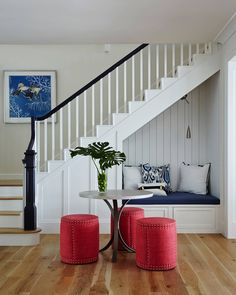 there is a table and two stools on the floor in front of the stairs