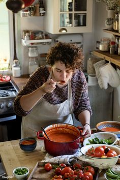 a woman in an apron preparing food on a kitchen counter with tomatoes and green beans