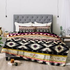 a bed covered in a black and white bedspread with colorful designs on it